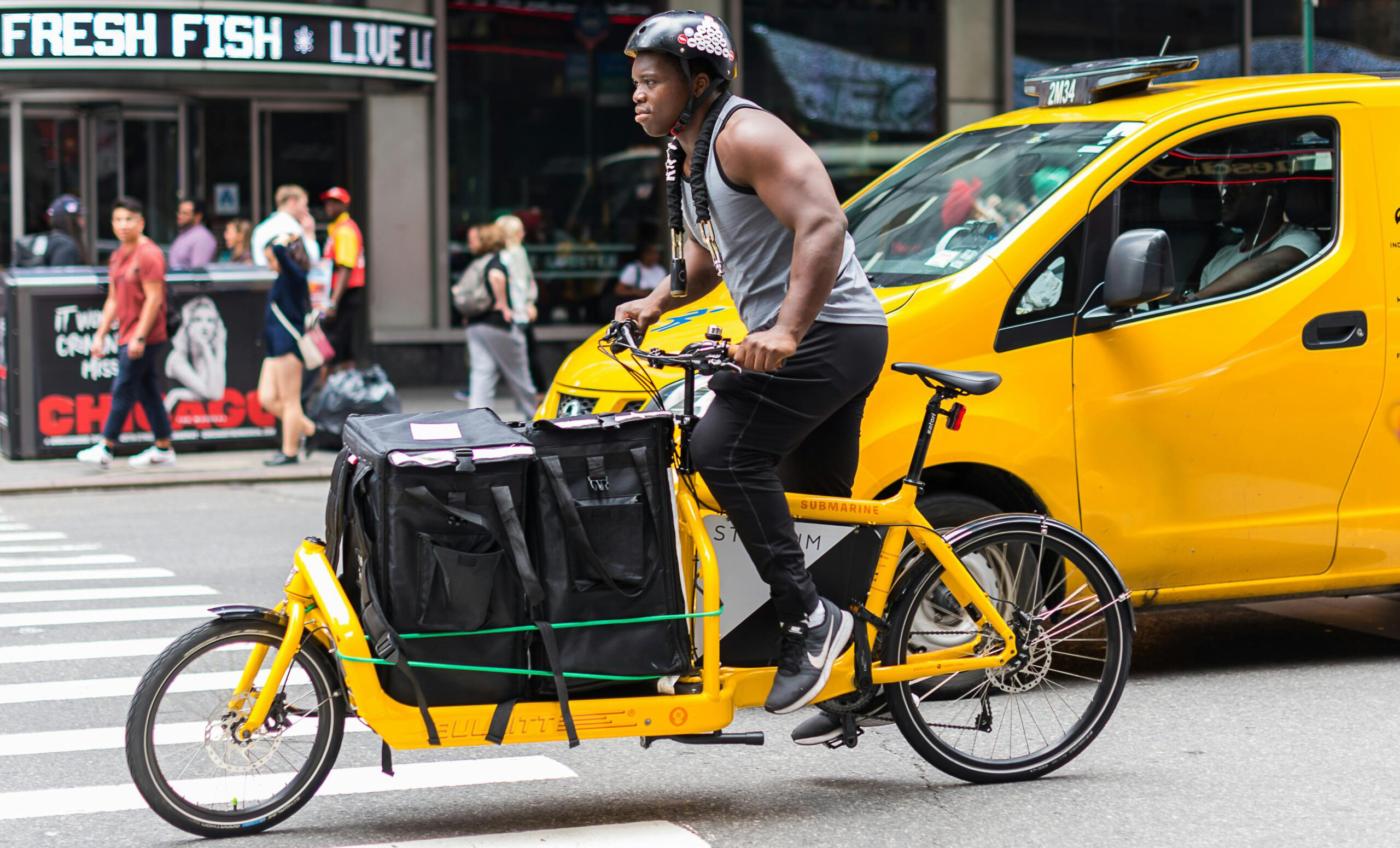 photo de cycliste sur vélo cargo éléctrique jaune dans la rue, solution écologique d'Ekoho